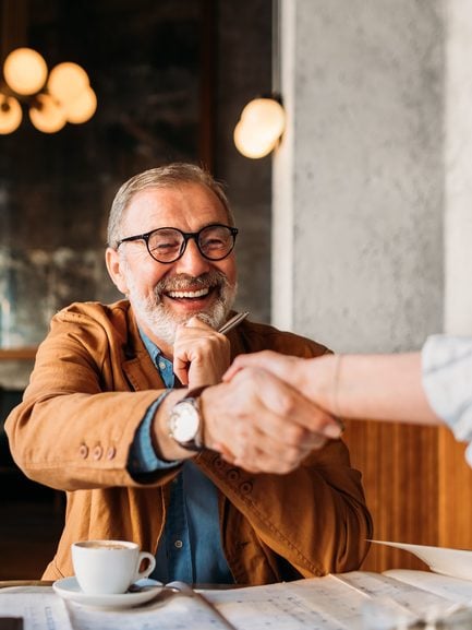 Businessman and businesswoman greeting each other, shaking hands in restaurant