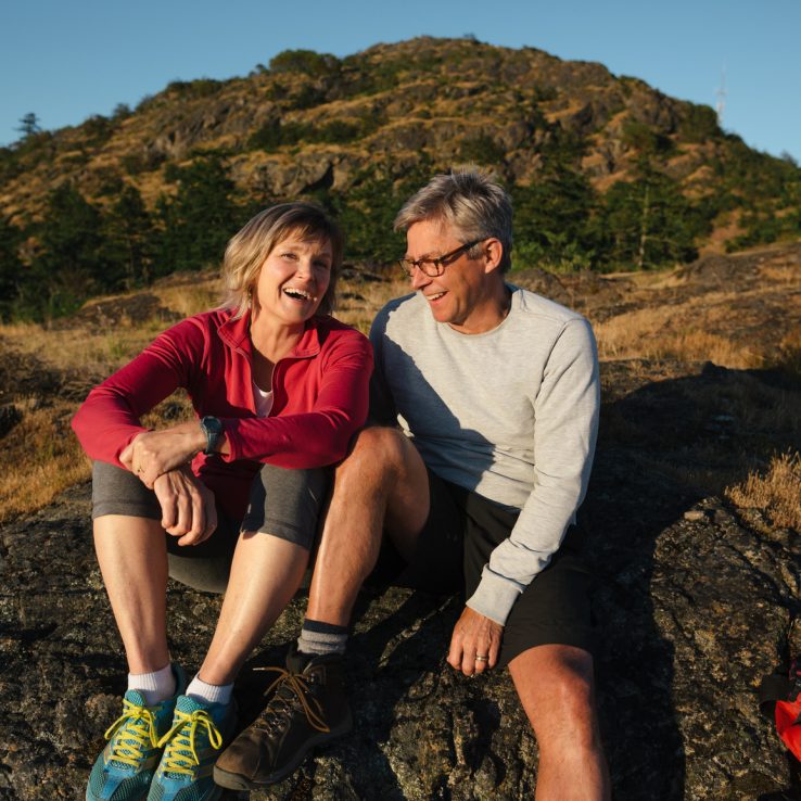 Middle age couple sits on a rock after a hike after sunset.