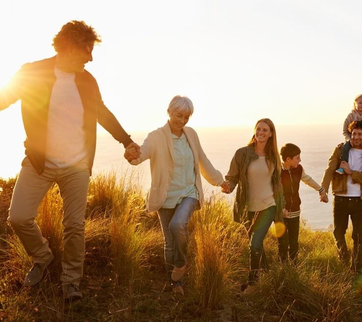 Multi-generational family holding hand walking up hill